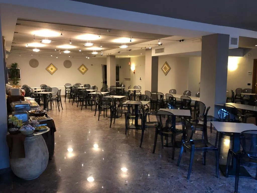 Sala ristorante con tavoli, sedie trasparenti e buffet allestito