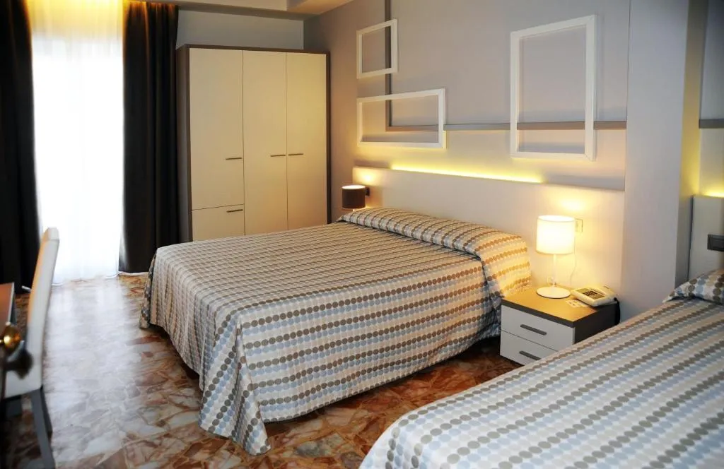 Camera con letto matrimoniale e letto singolo, armadio chiaro e illuminazione soffusa