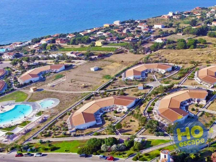 Veduta aerea del resort con piscina, edifici e mare sullo sfondo