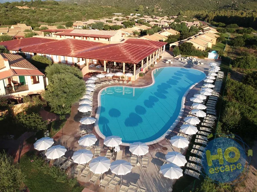 Vista aerea della grande piscina curva circondata da ombrelloni e lettini bianchi