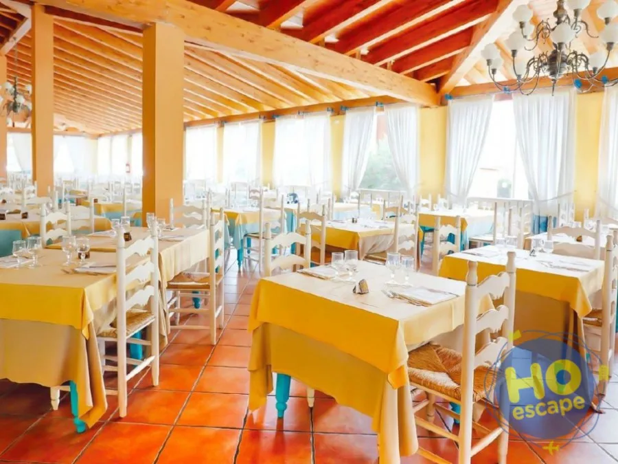 Sala ristorante luminosa con tavoli dalle tovaglie gialle e pavimento in cotto