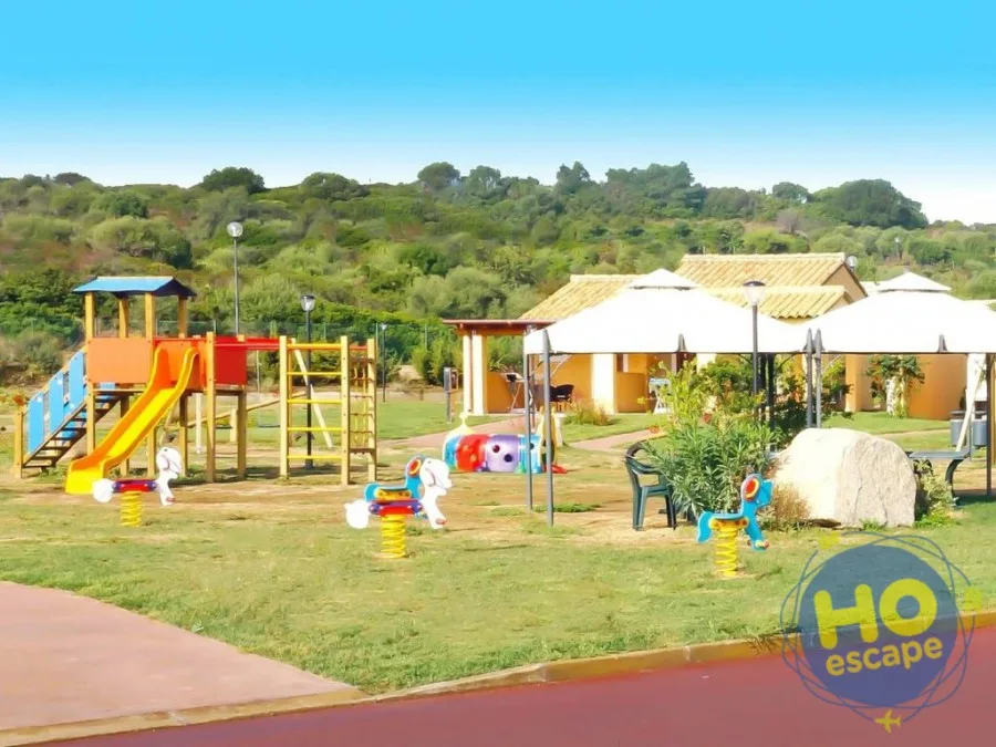 Area giochi per bambini con scivolo, giostrine a molla e prato verde