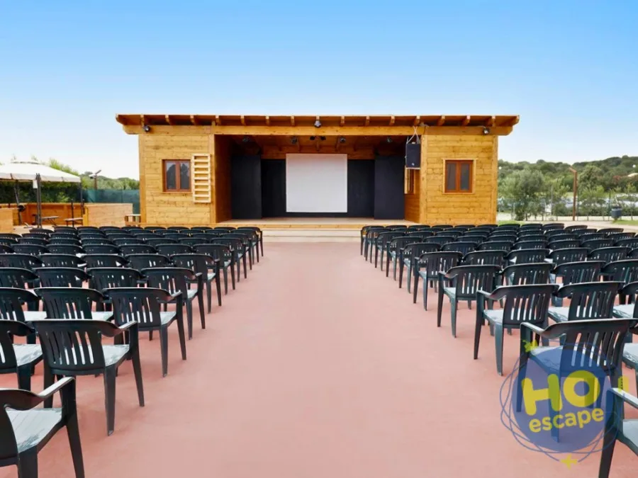Anfiteatro all'aperto con palco in legno e file di sedie per spettacoli serali