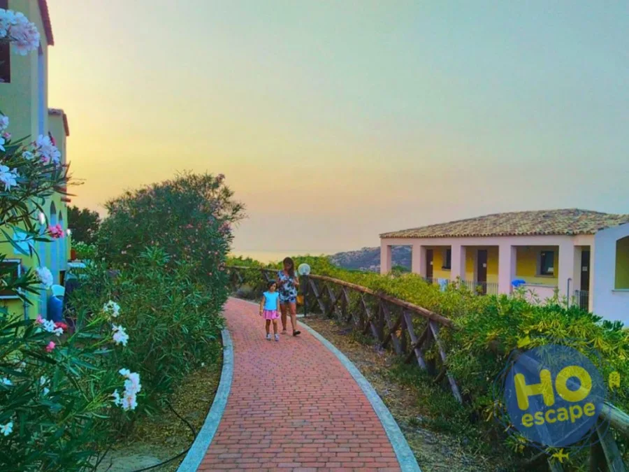 Vialetto in mattoni tra gli alloggi con fiori al tramonto e vista mare
