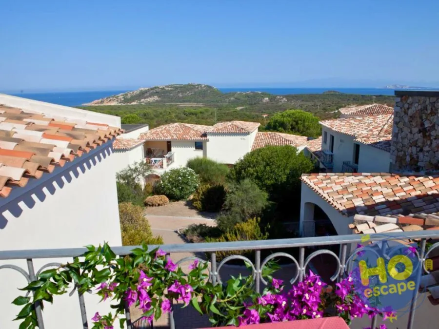 Vista mare dal balcone con fiori di bouganville e tetti in coppi
