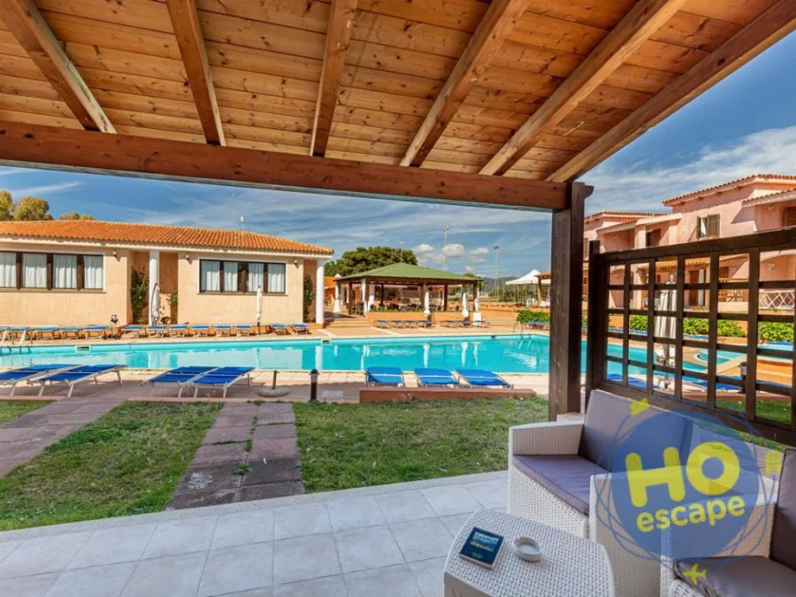 Veranda coperta in legno con divano in vimini affacciata sulla piscina