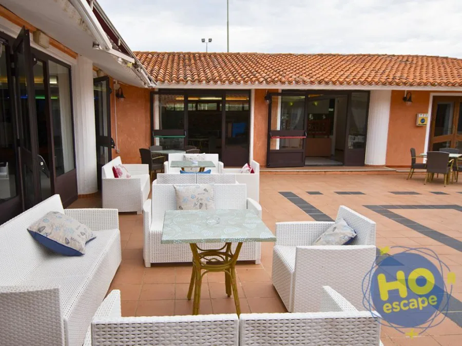 Terrazza esterna con divani in rattan bianco, tavolini e area relax