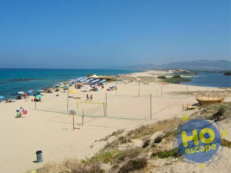 Ampia spiaggia sabbiosa con ombrelloni, campo da beach volley e laguna sullo sfondo