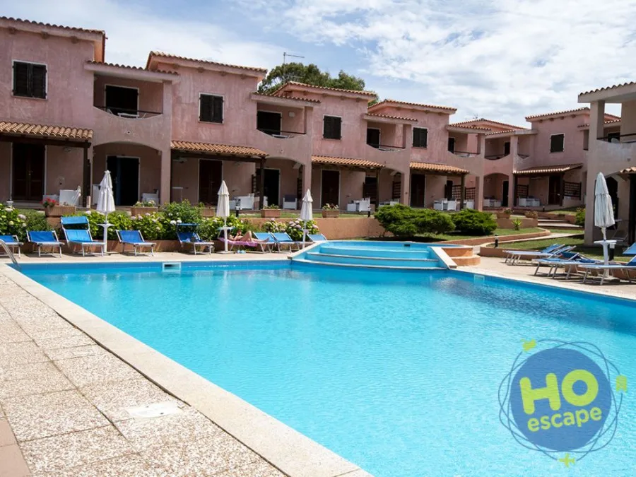 Piscina esterna con lettini blu circondata da residence in muratura rosa