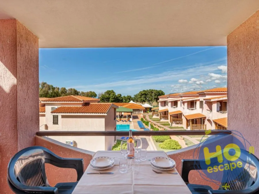 Tavolo apparecchiato sul balcone con vista sulla piscina e sul residence