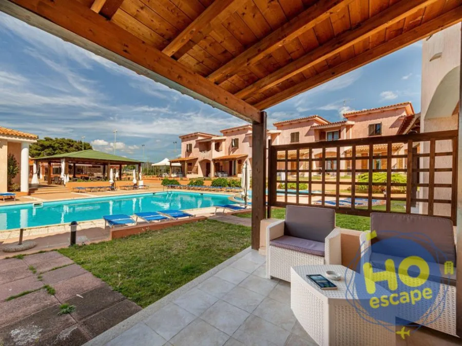 Veranda con divani in rattan e tettoia in legno affacciata sulla piscina