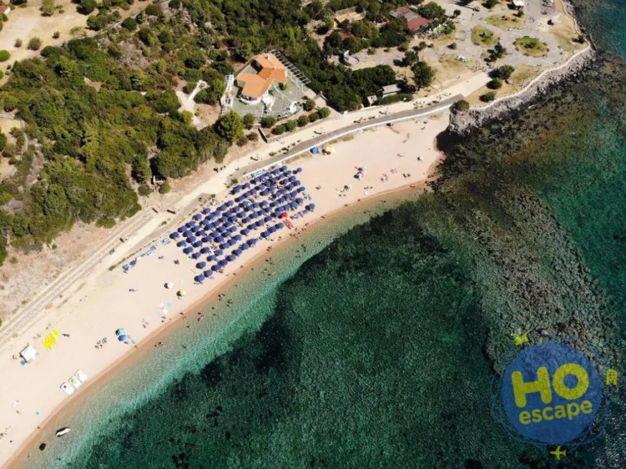Veduta dall'alto della spiaggia con ombrelloni blu e acque limpide