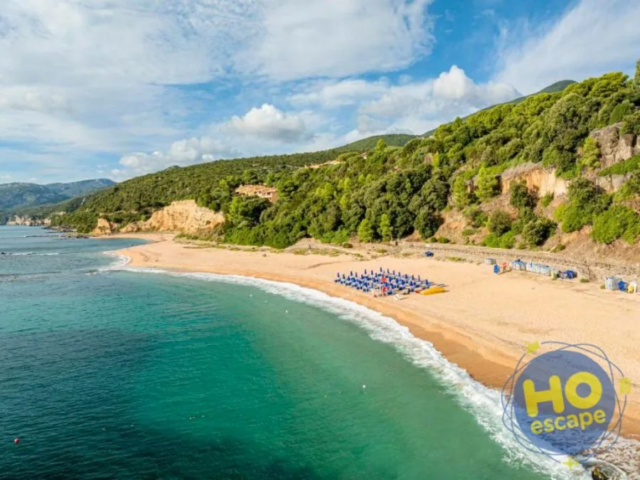 Spiaggia con sabbia dorata, mare turchese e colline verdeggianti