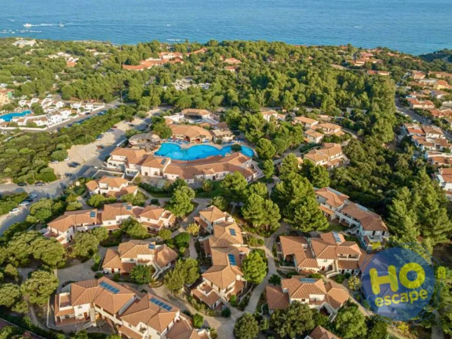 Vista aerea del resort con piscina, casette e mare sullo sfondo