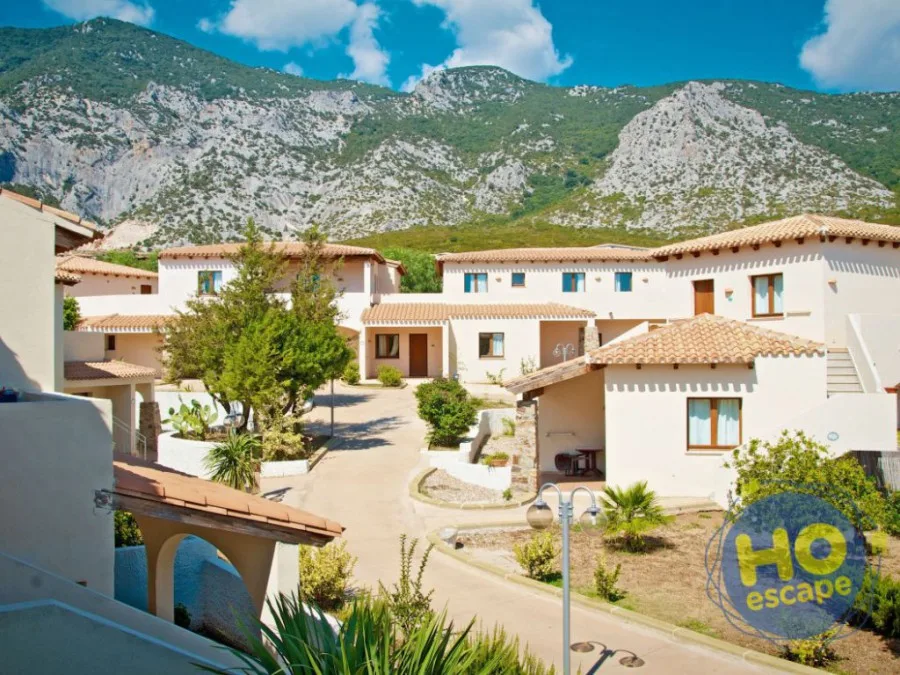 Villette bianche del resort con tetti in tegole circondate dalle montagne della Sardegna