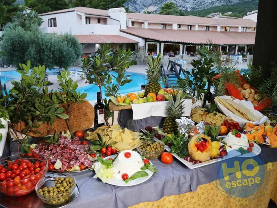 Ricco buffet all'aperto con salumi, formaggi, verdure e frutta fresca vicino alla piscina
