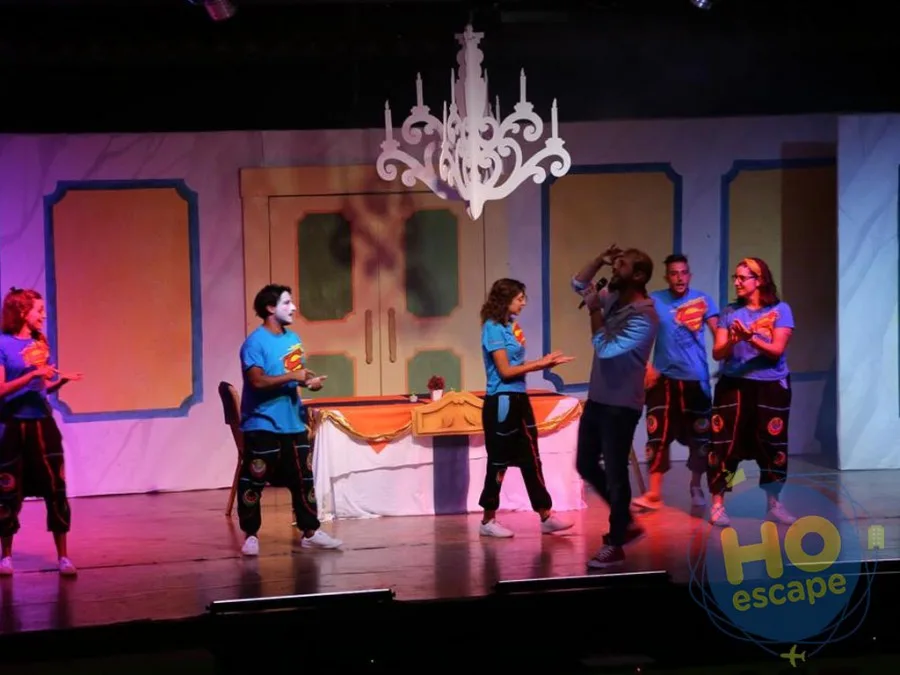 Spettacolo serale con animatori in maglietta blu che cantano sul palco del teatro