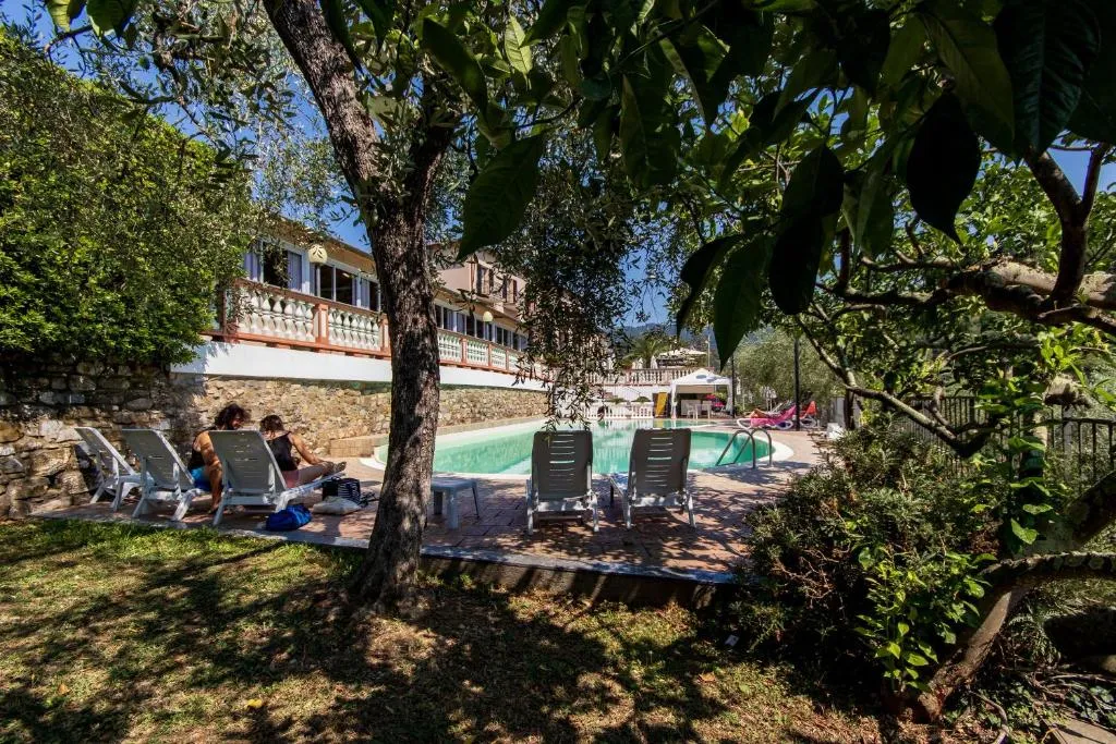 Giardino ombreggiato con lettini e ospiti accanto alla piscina