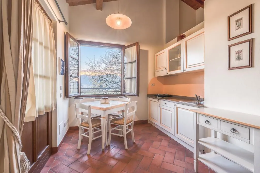 Cucina rustica con mobili bianchi, tavolo da pranzo e finestra con vista