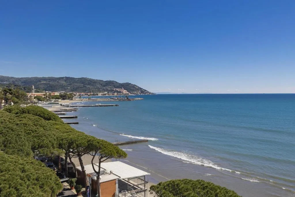 Vista panoramica sulla costa ligure con spiaggia, pini marittimi e mare azzurro