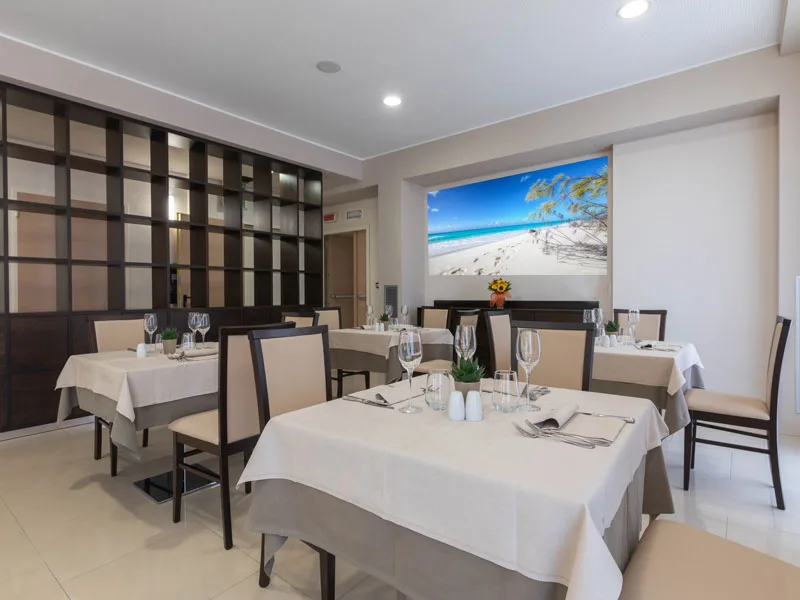 Sala ristorante elegante con tavoli apparecchiati e quadro di spiaggia