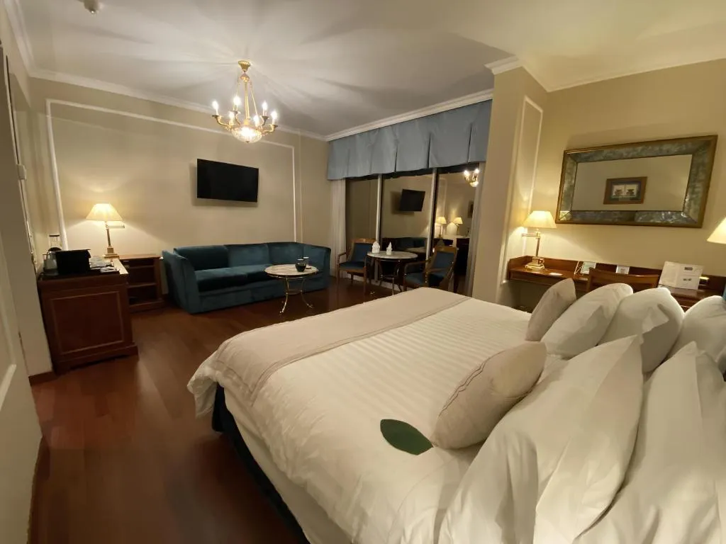 Camera elegante con letto matrimoniale, divano blu, lampadario e pavimento in legno