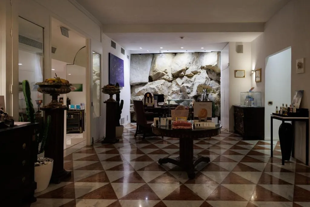 Area benessere e shop con pavimento a scacchi, parete in pietra e prodotti cosmetici esposti