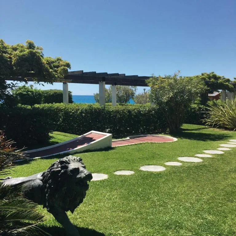 Giardino con prato verde, pergolato, mini golf e statua di leone affacciato sul mare