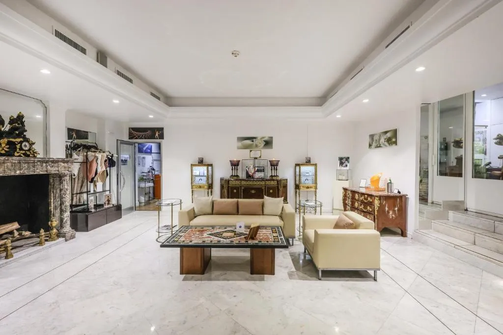 Salone elegante con divani crema, camino in marmo, tavolino e arredi d'epoca