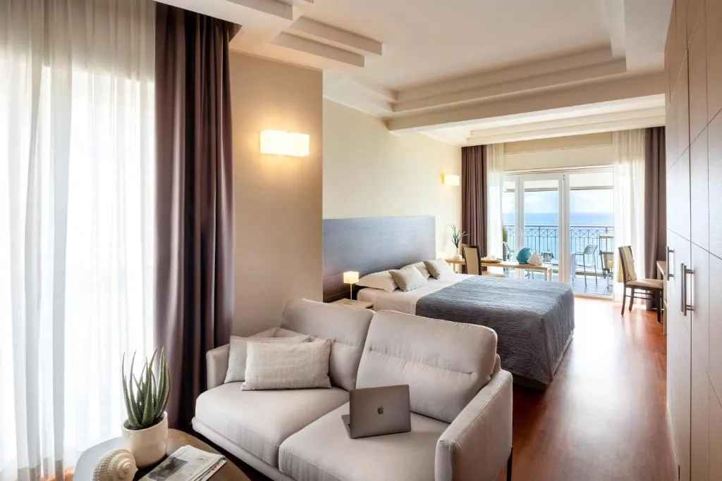 Ampia camera con divano, letto matrimoniale e balcone affacciato sul mare