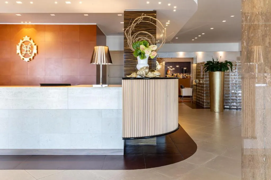 Reception elegante dell'hotel con bancone in marmo e composizione floreale