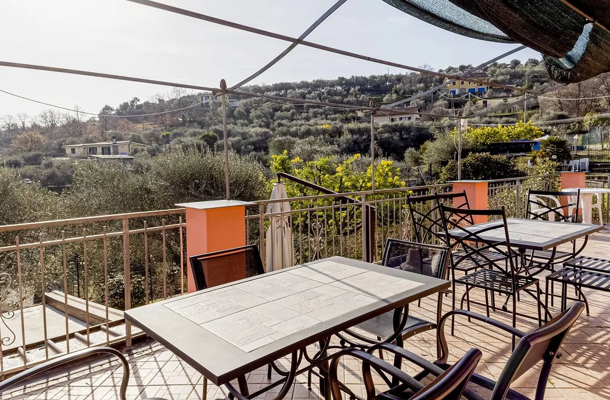 Terrazza panoramica con tavoli e sedie e vista sulle colline e gli uliveti
