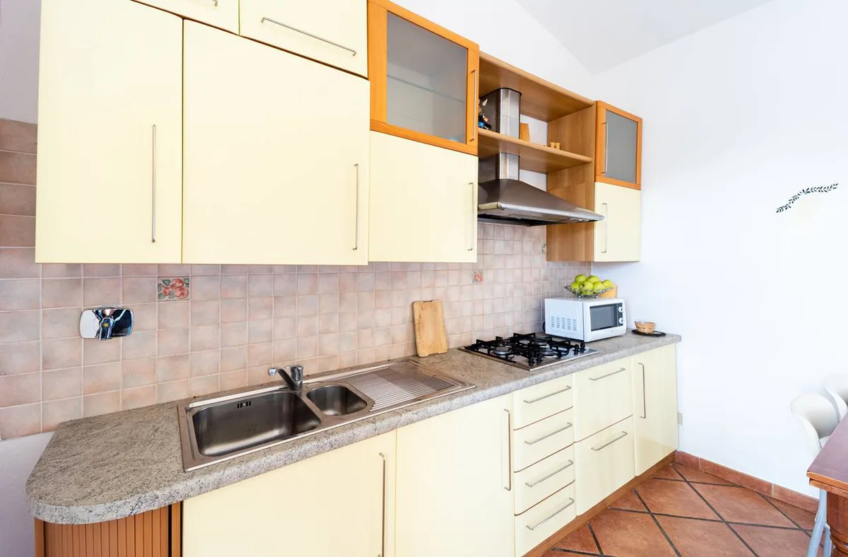 Cucina lineare con mobili gialli, piano cottura a gas e microonde