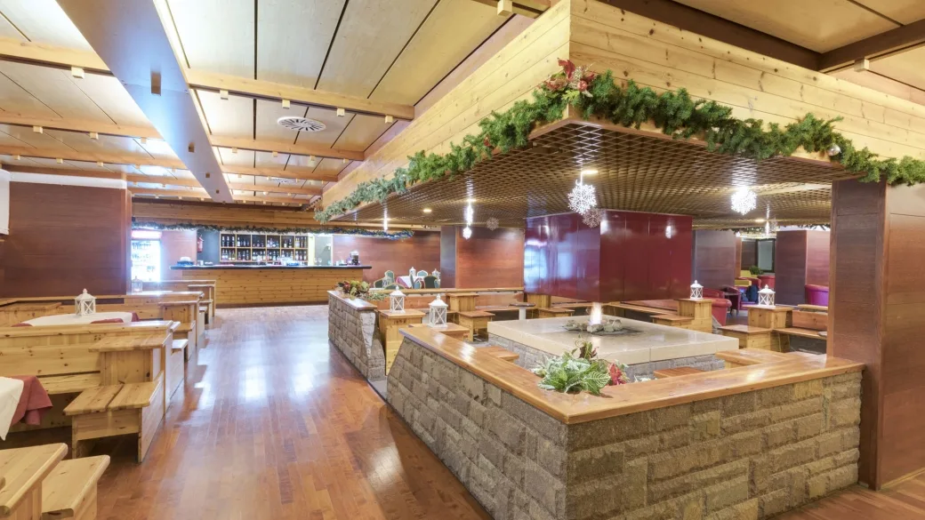 Area lounge e bar in stile alpino con arredi in legno, panche e decorazioni natalizie