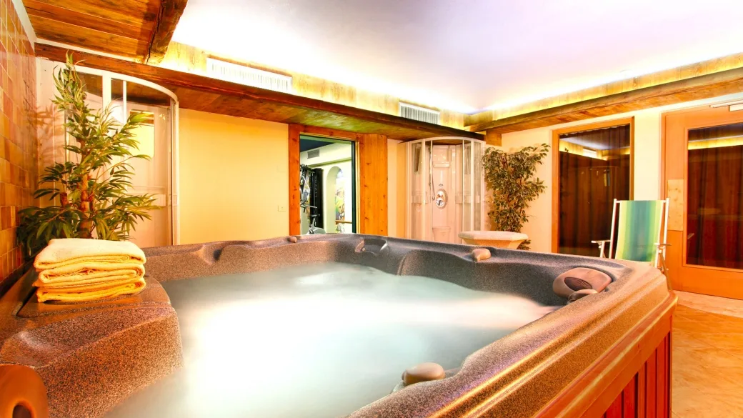 Area spa con vasca idromassaggio, docce emozionali e piante decorative