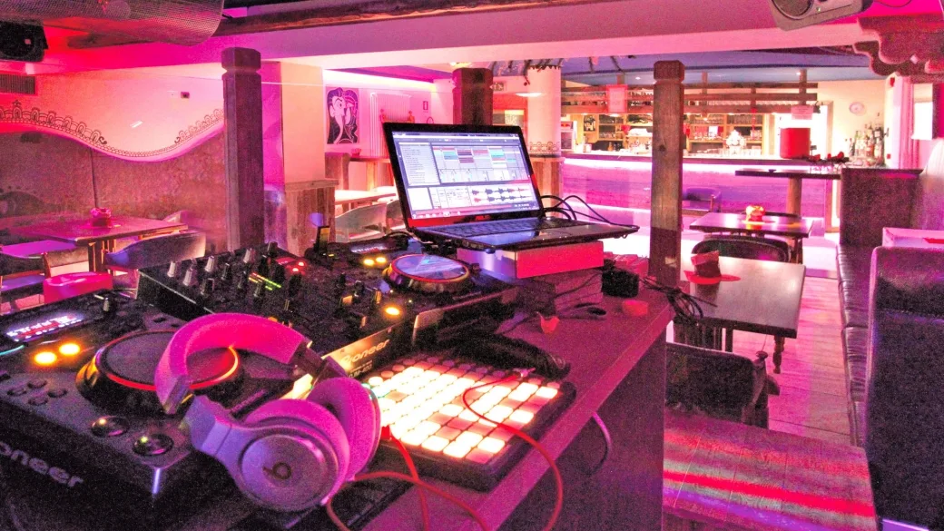 Discoteca dell'hotel con consolle da DJ, cuffie e illuminazione rosa