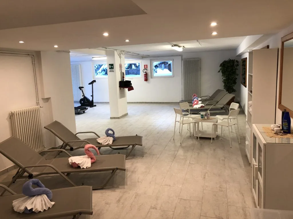 Zona relax spa con lettini, cyclette e asciugamani decorativi