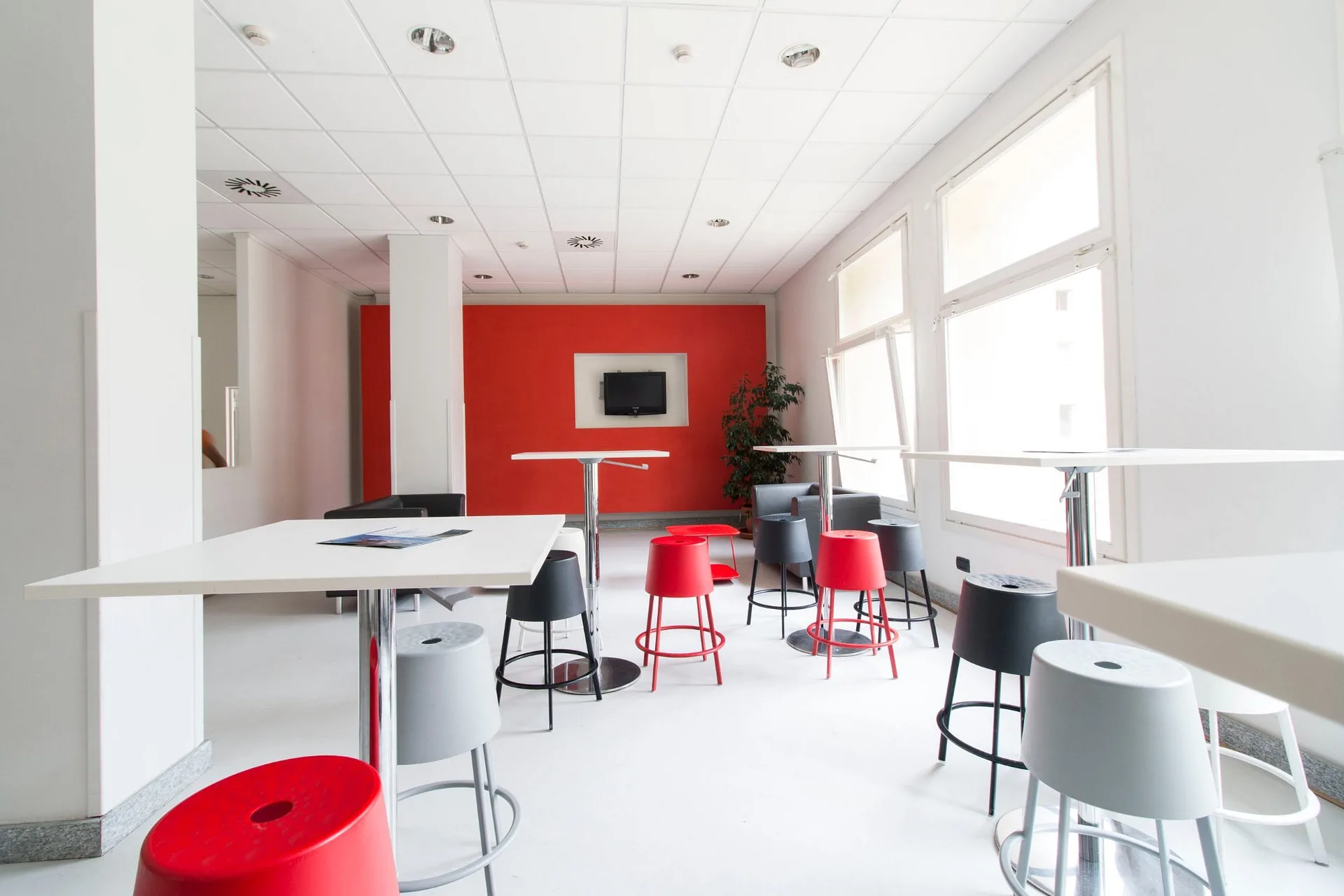 Sala lounge moderna con sgabelli rossi e grigi e parete rossa