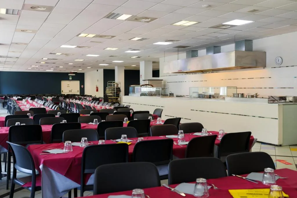 Sala da pranzo con tavoli rossi e zona buffet self-service