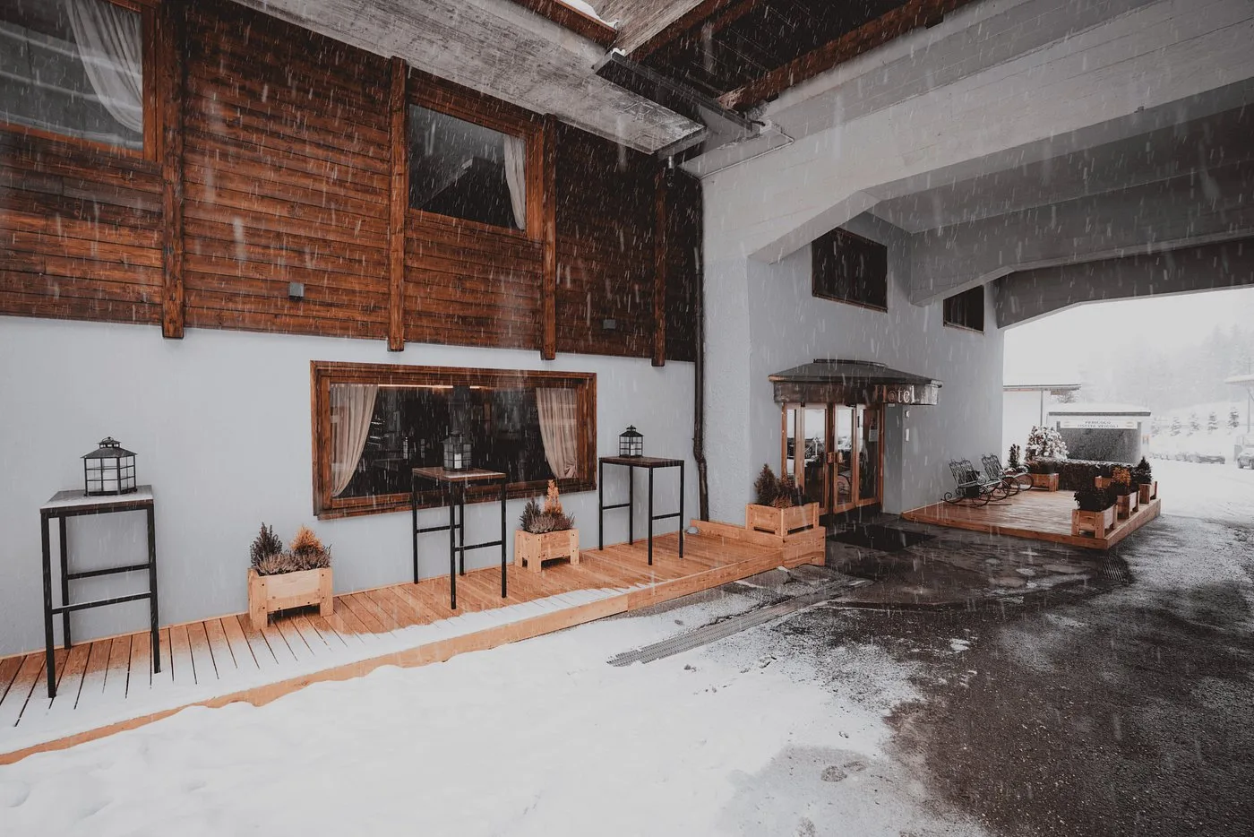 Ingresso coperto dell'hotel con terrazza in legno sotto la nevicata