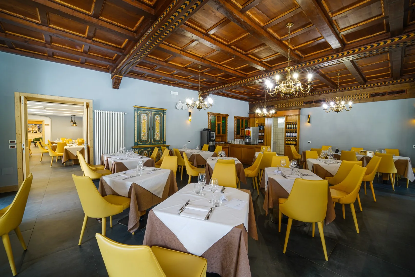Sala ristorante con soffitto in legno decorato, lampadari e mobili tradizionali dipinti