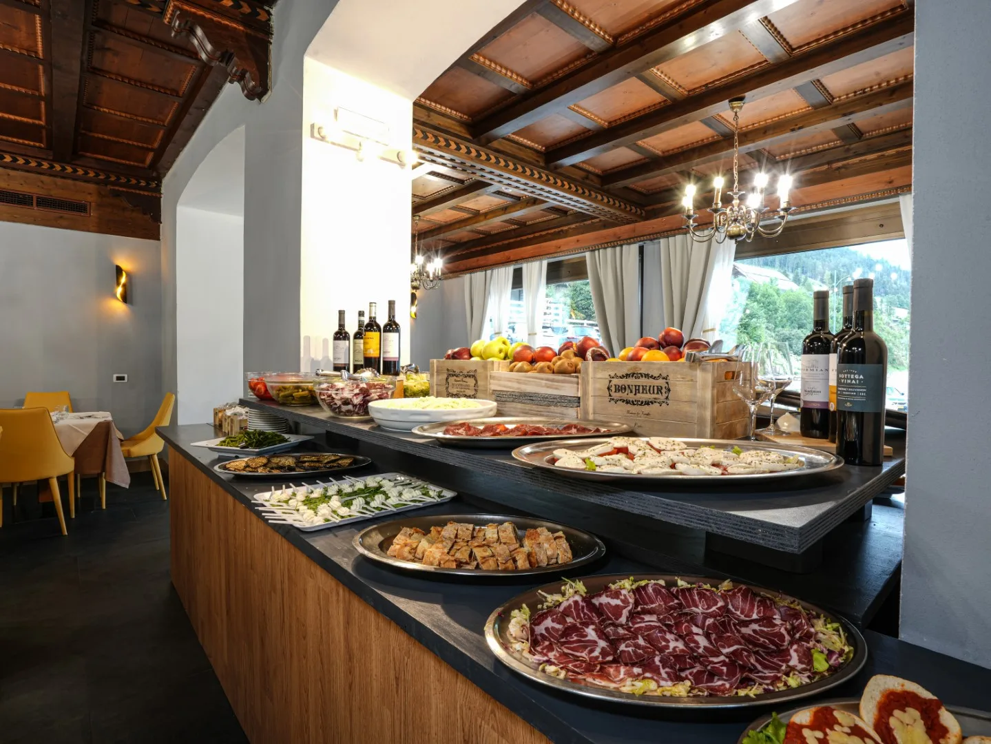 Buffet ricco di salumi, formaggi, verdure e frutta con bottiglie di vino sul bancone