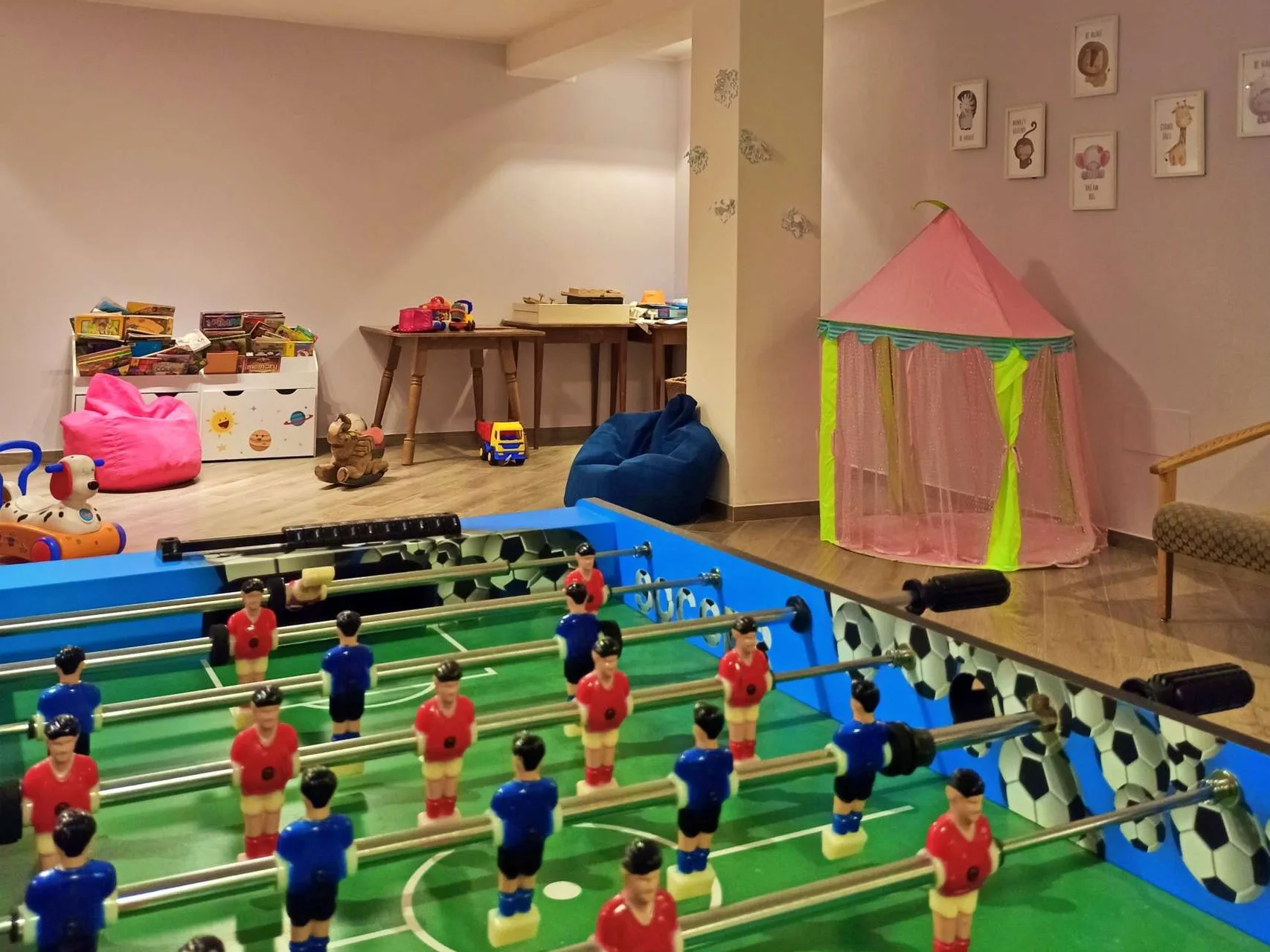 Sala giochi per bambini con calcio balilla, tenda rosa e giocattoli