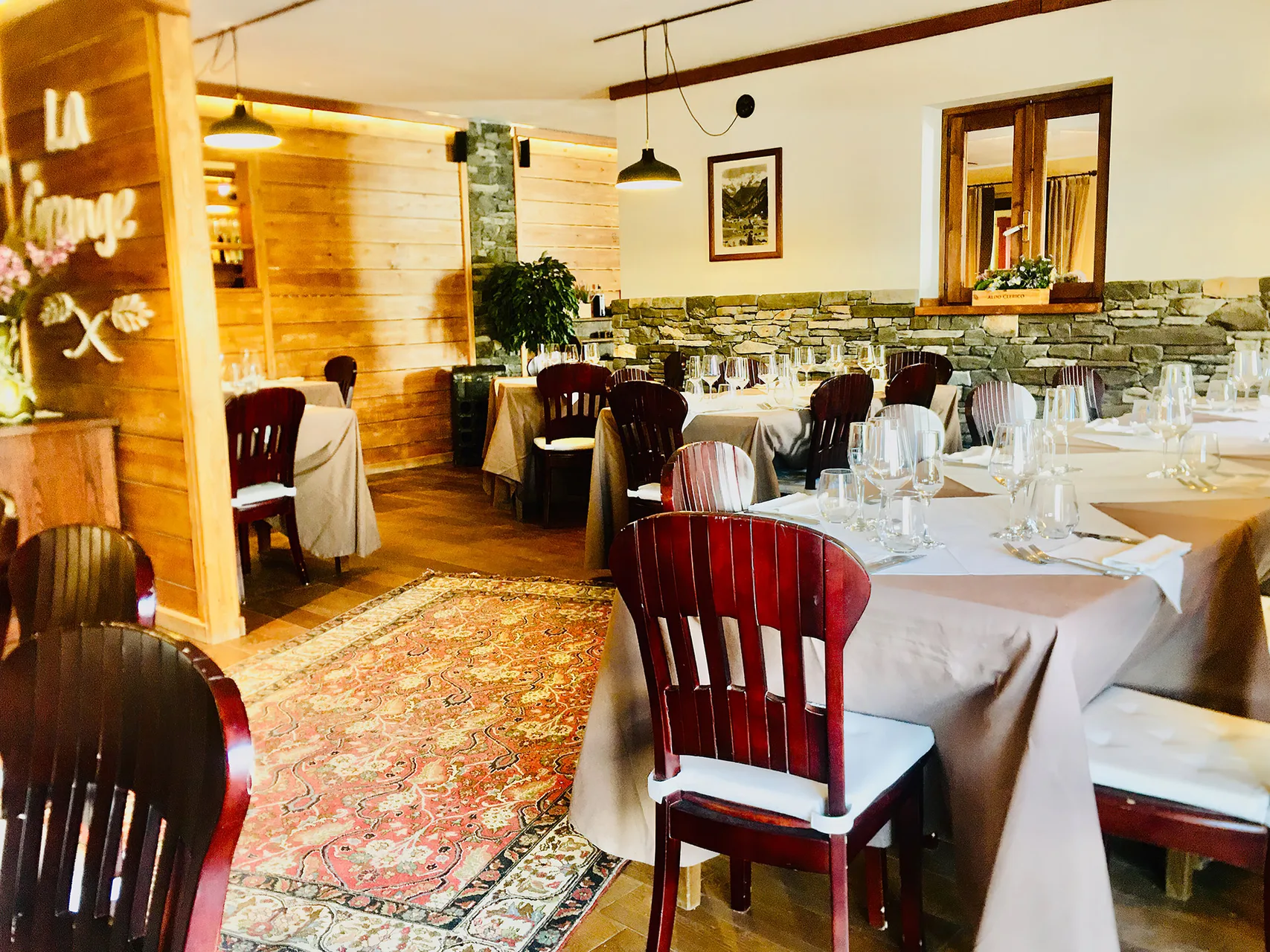 Sala ristorante La Grange con tavoli apparecchiati, sedie in legno e tappeto orientale