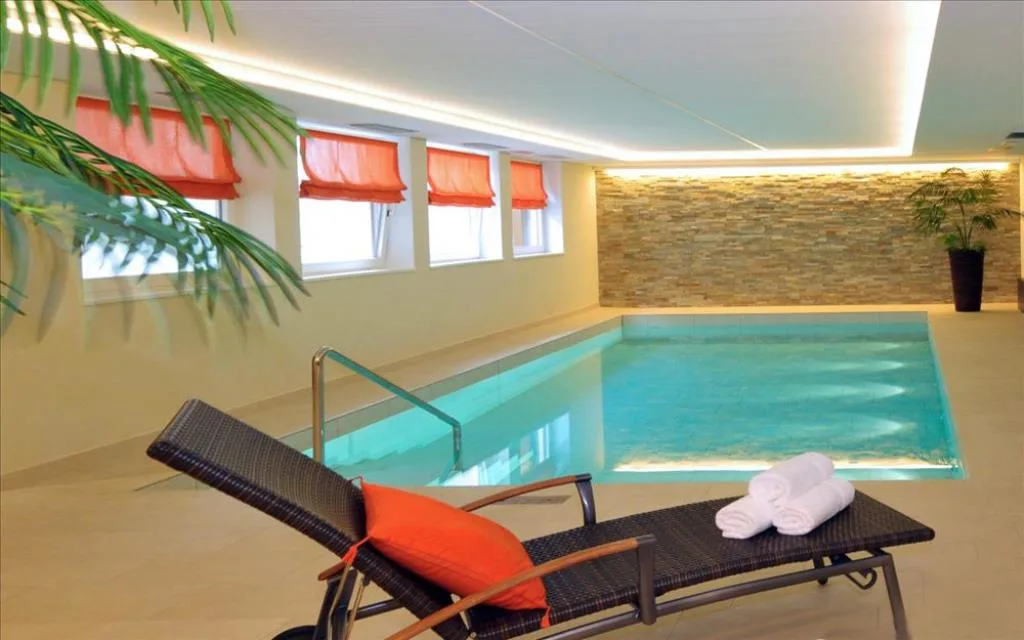 Piscina interna con lettino, asciugamani e parete in pietra