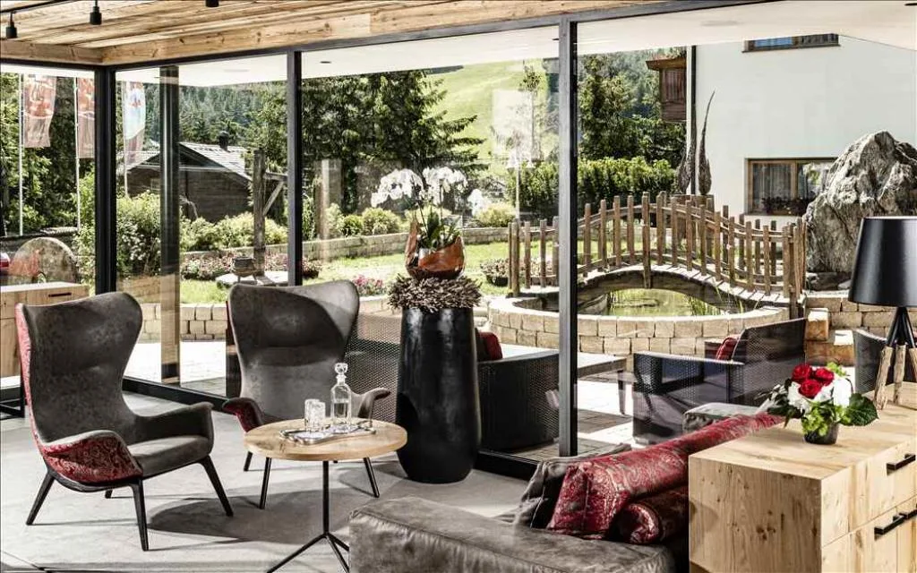 Salotto luminoso con poltrone di design e ampie vetrate sul giardino con laghetto