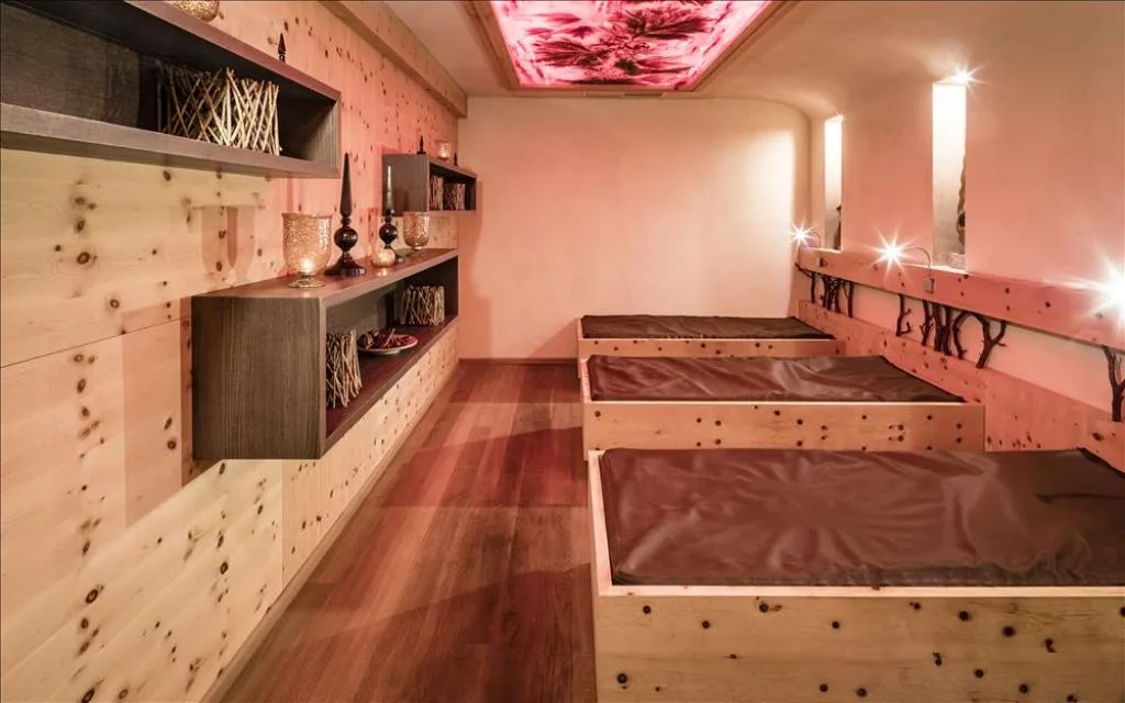 Area relax della spa con lettini in legno di cirmolo e illuminazione soffusa rosata