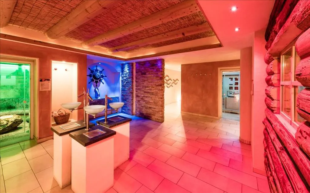 Area wellness con docce emozionali, illuminazione colorata e accesso alle saune