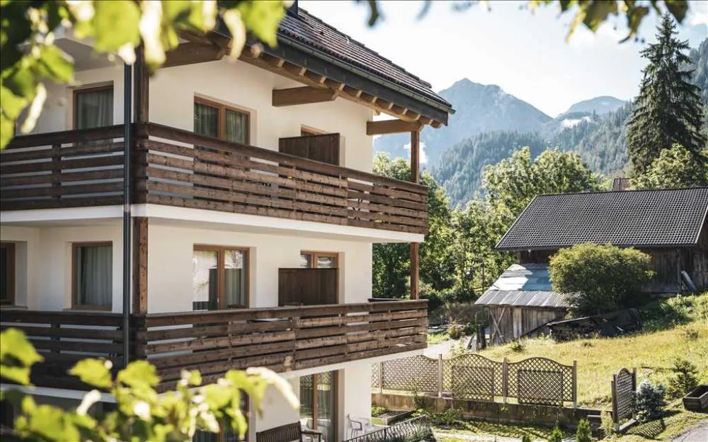 Dettaglio della facciata dell'hotel con balconi in legno immerso nel verde estivo