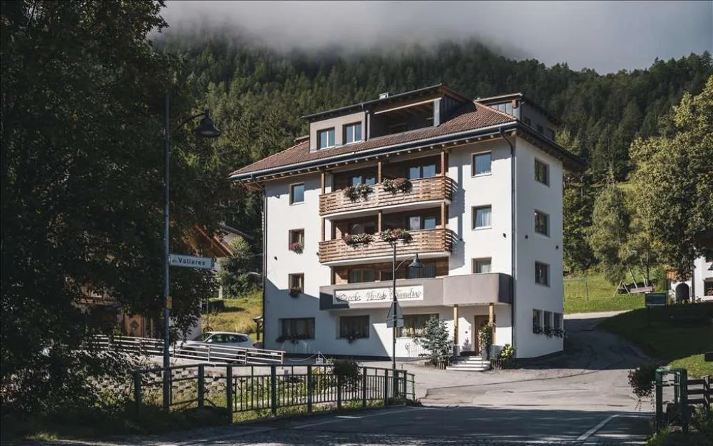 Esterno dell'hotel con balconi fioriti circondato dal bosco